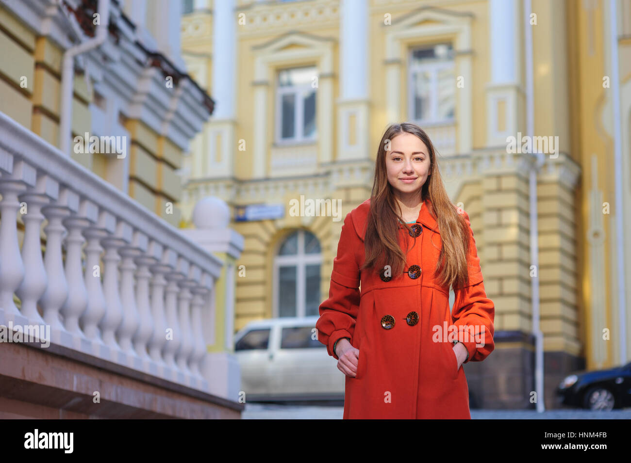 junge Frau in orange Mantel posiert in der Altstadt Stockfoto