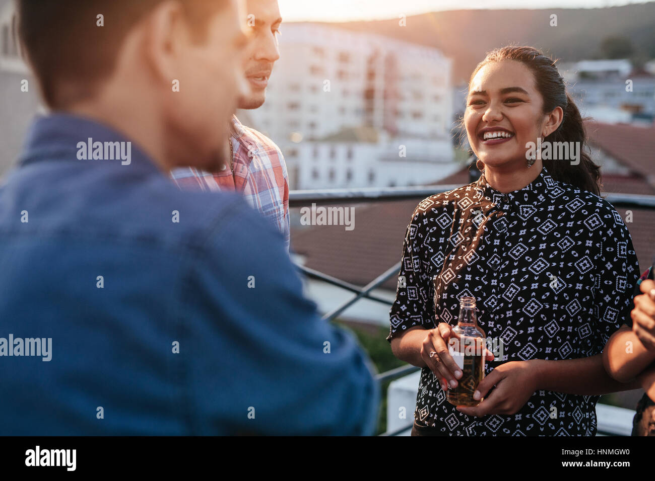 Lächelnde junge Frau auf dem Dach mit Freunden Bier stehend festhalten. Menschen, die gute Zeit auf Party. Stockfoto