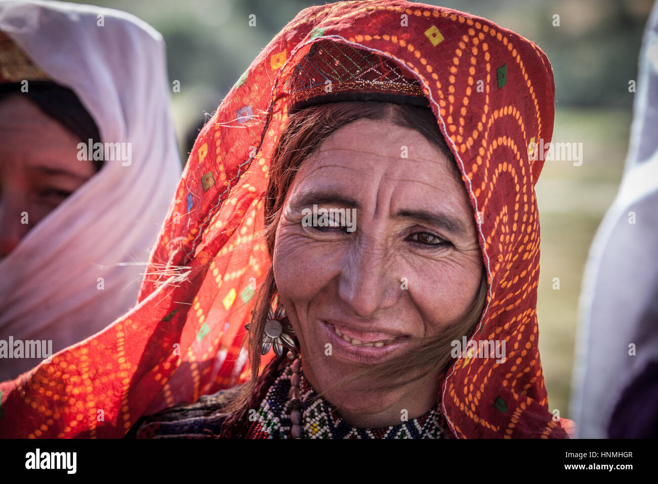 Afghanistan, Wakhan-Korridor, ein Porträt einer lächelnden Frau mit roten Schleier. Stockfoto