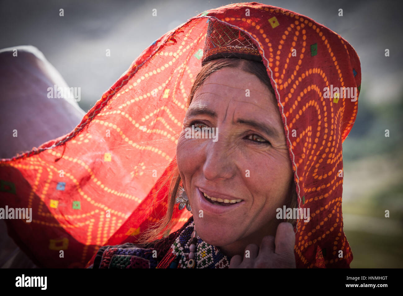 Afghanistan, Wakhan-Korridor, ein Porträt einer lächelnden Frau mit roten Schleier. Stockfoto