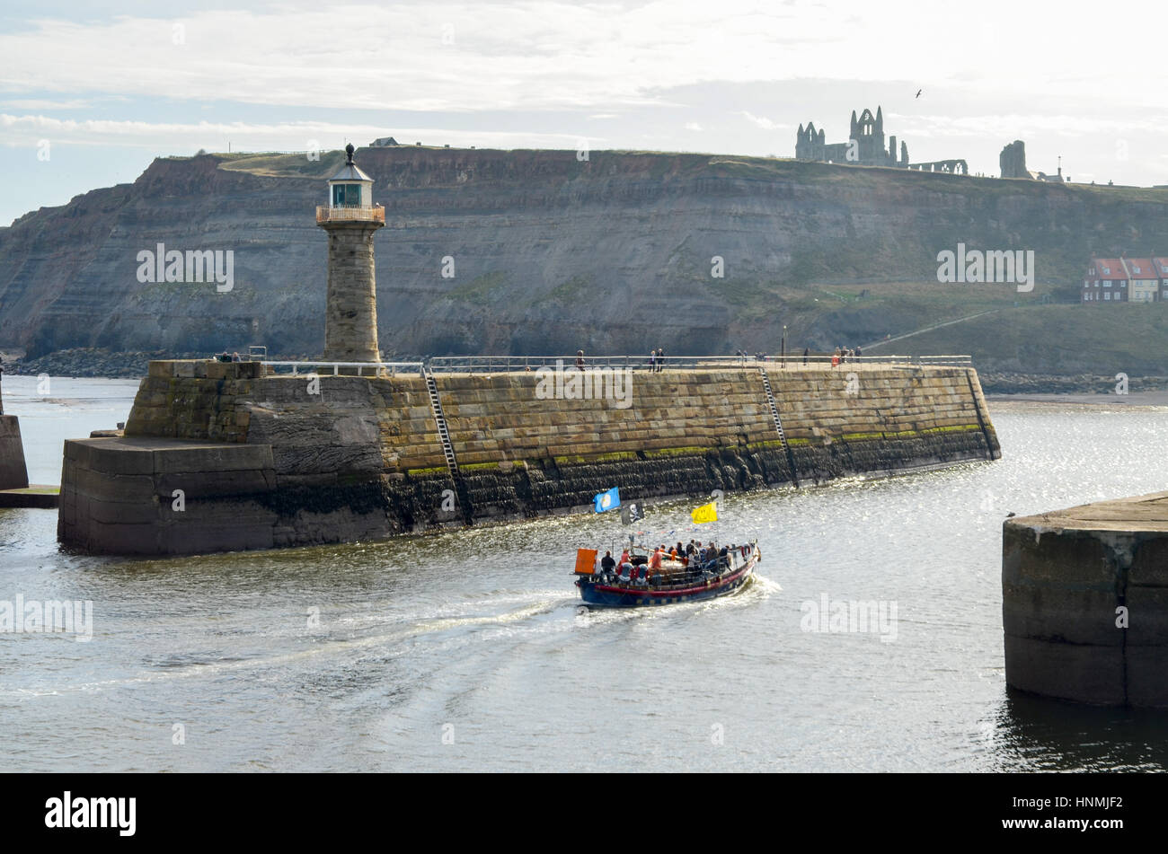 Leuchtturm mit Whitby Abtei und Kirche der Heiligen Maria im Hintergrund. Touristischen Rettungsboot im Vordergrund. Stockfoto