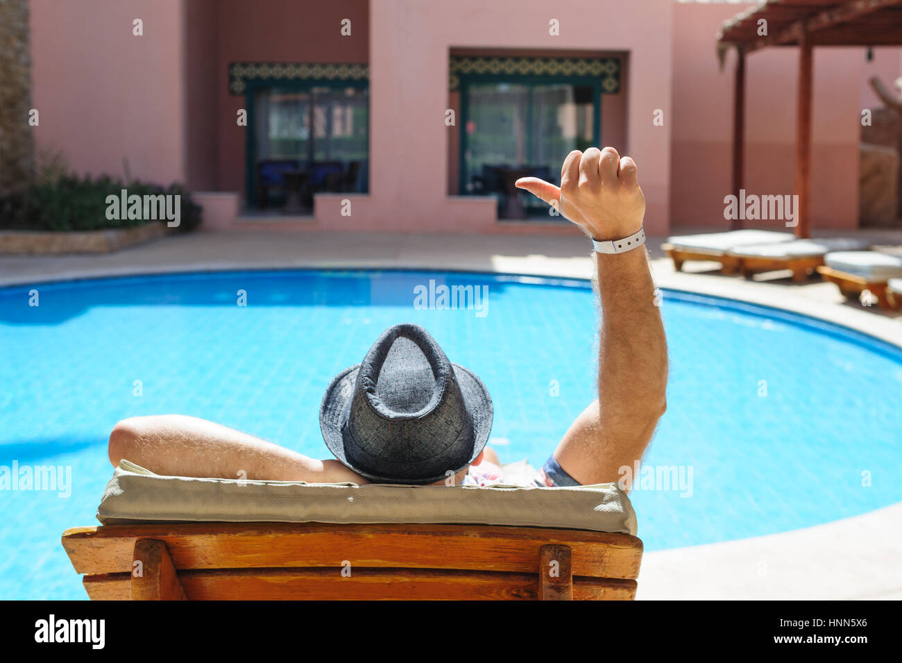 Mann mit Hut liegen auf einer Liege am Pool Stockfoto