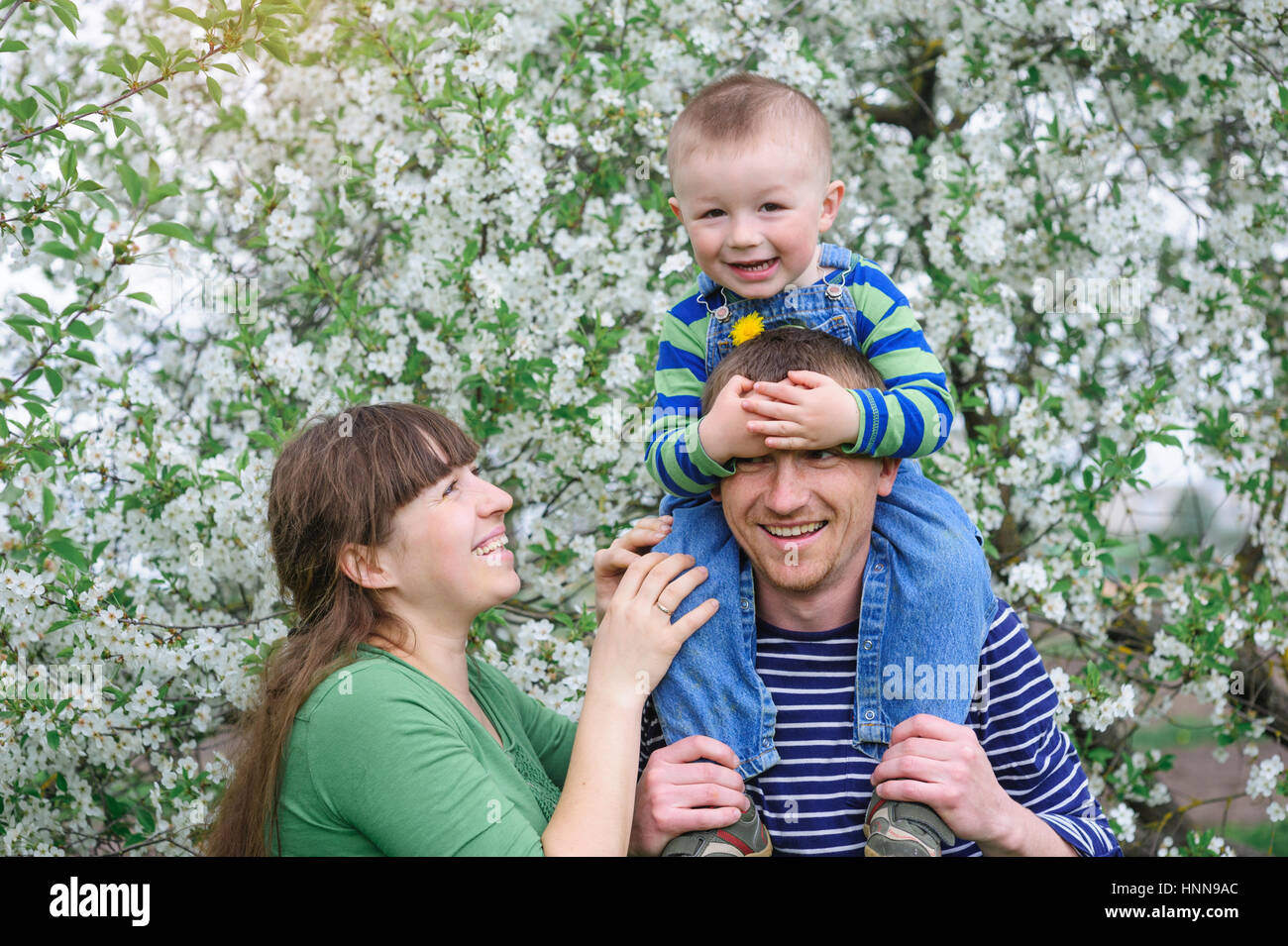 junge Familie und seinem kleinen Sohn in einen blühenden Frühling Garten Stockfoto