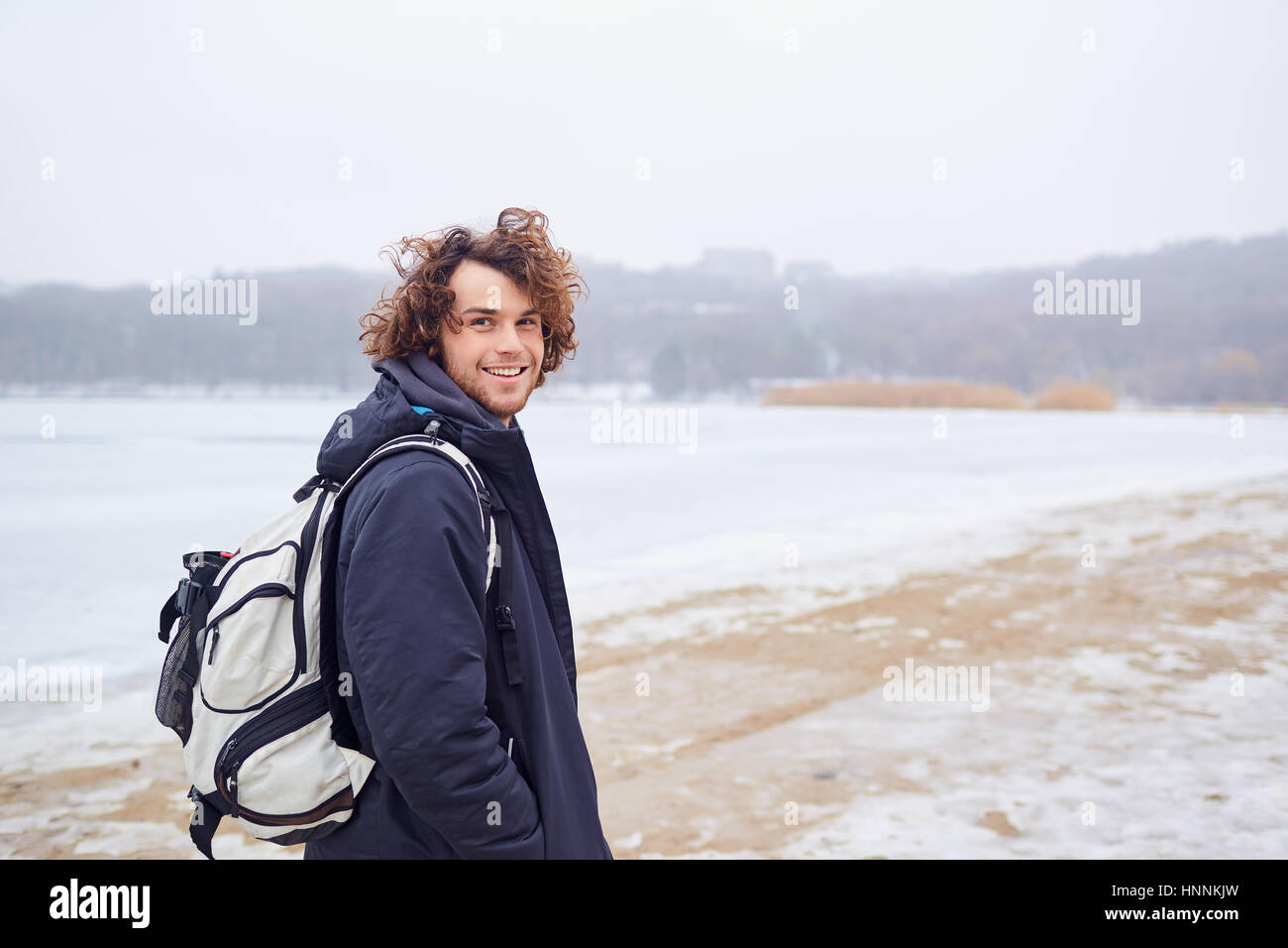 Junger Mann mit einem Rucksack auf der Natur der Winter Frühling Lächeln Stockfoto