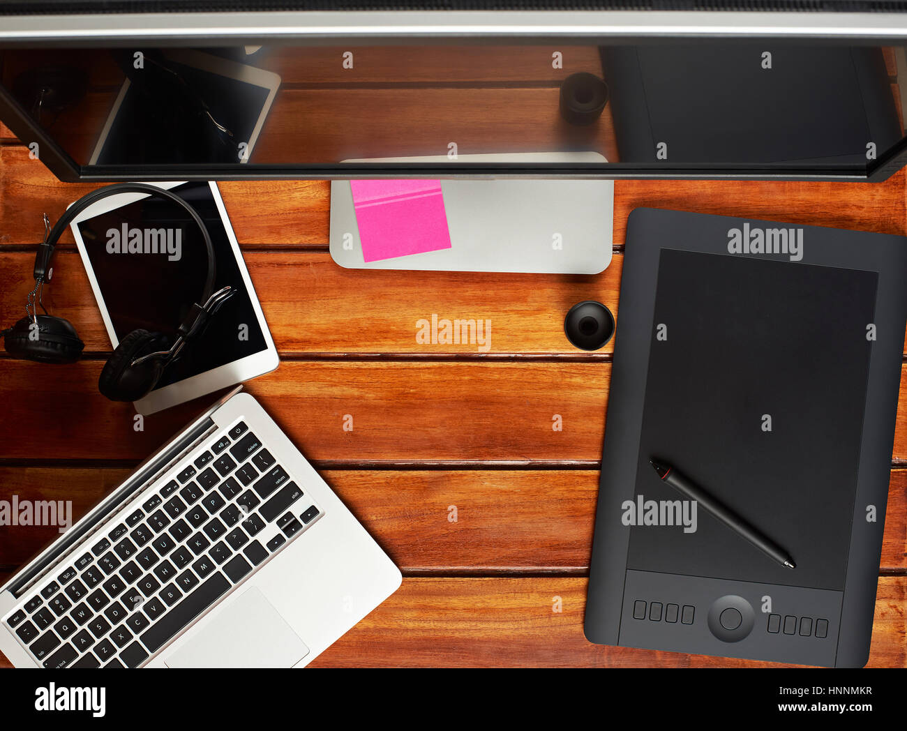 Großer Monitor für die Retusche mit Laptop und Grafiktablett auf Holztisch Hintergrund Stockfoto