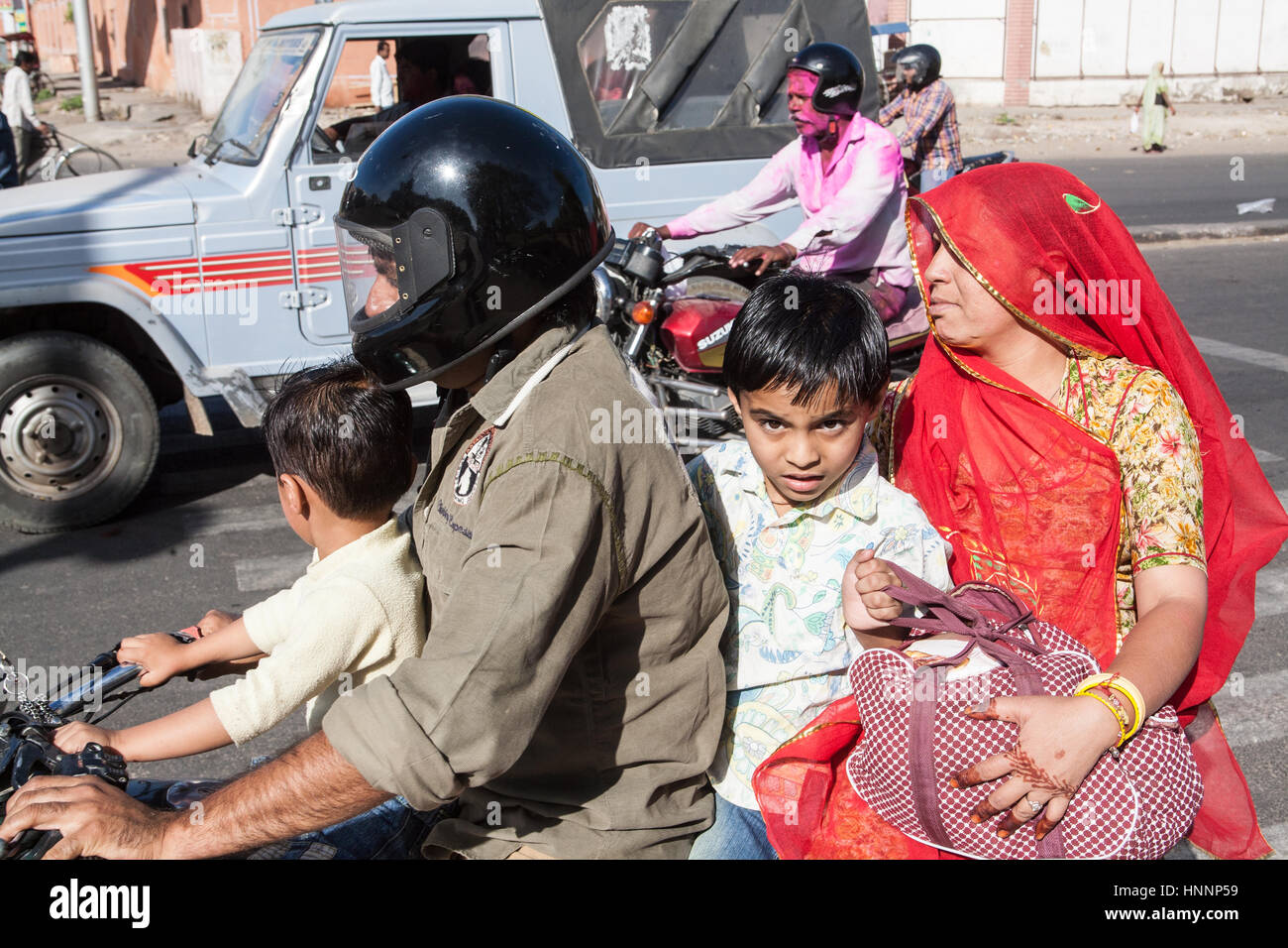 Vier Mitglieder der Familie auf dem Motorrad während der Frühlings-Event, Urlaub. Holi-Fest der Farbe. Jaipur,Rajasthan,India,Asia.Rider mit Helm. Kein Helm Stockfoto