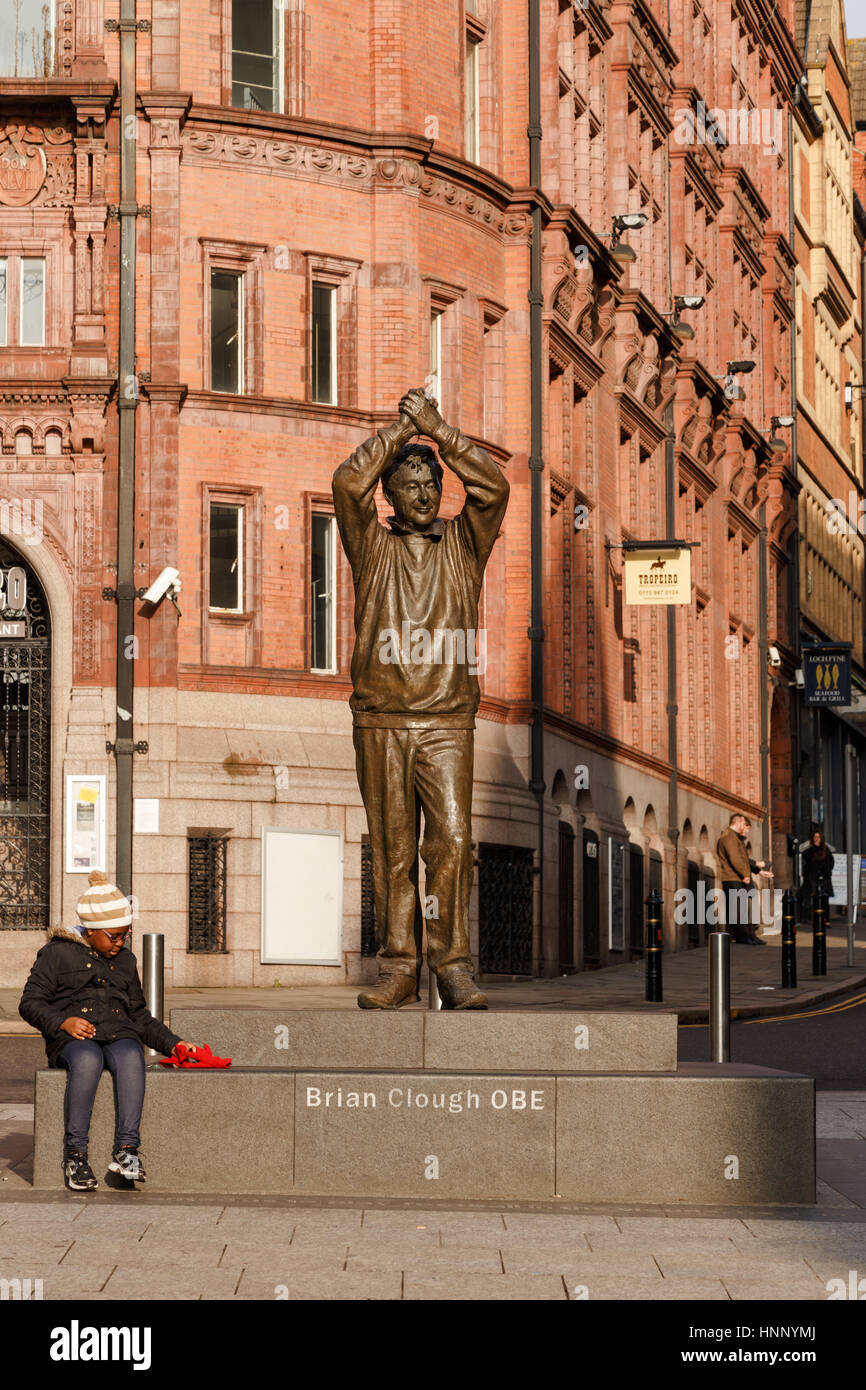 Nottingham, England - 13. Februar: Wenig schwarz/afro-karibischen Junge sitzt neben Brian Clough Statue in Nottingham, Nottingham, England. Am 13. t Stockfoto