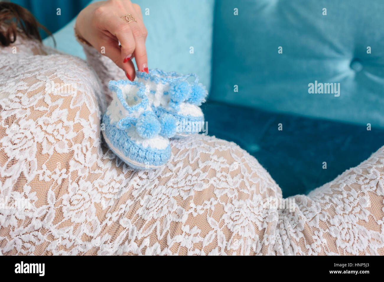 Schwangere Frau mit Bauch an die gestrickte Babyschuhe Stockfoto
