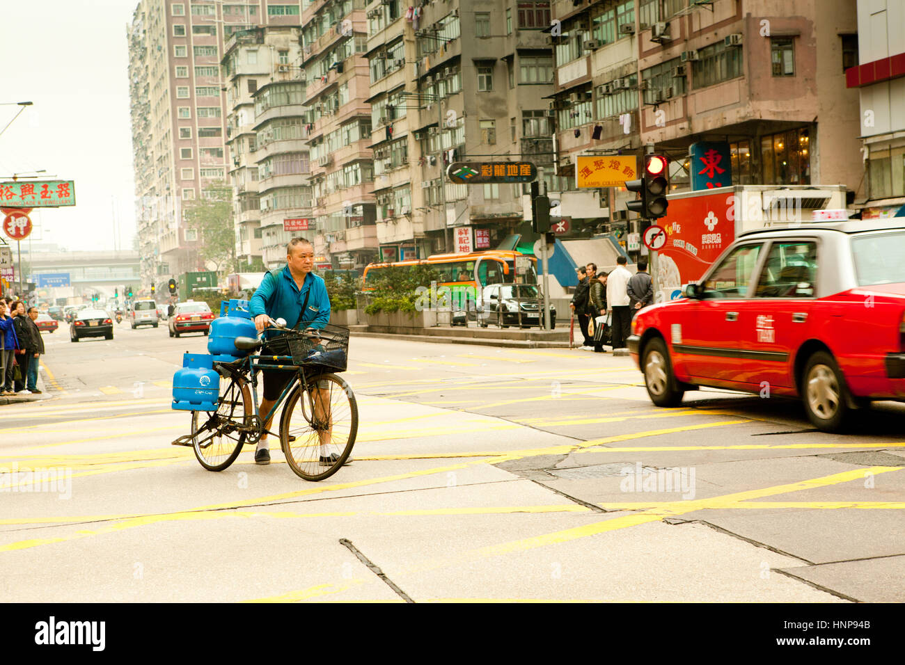 Hochrangige chinesische Mann beim Überqueren der Straße mit dem Fahrrad, Kowloon, Hong Kong Stockfoto