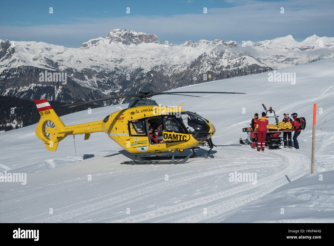 Verletzte Skifahrer wird mit dem Schneemobil in Rettungshubschrauber ÖAMTC, Silvretta Montafon, Kapellalpe, Dorf von Schruns transportiert. Stockfoto