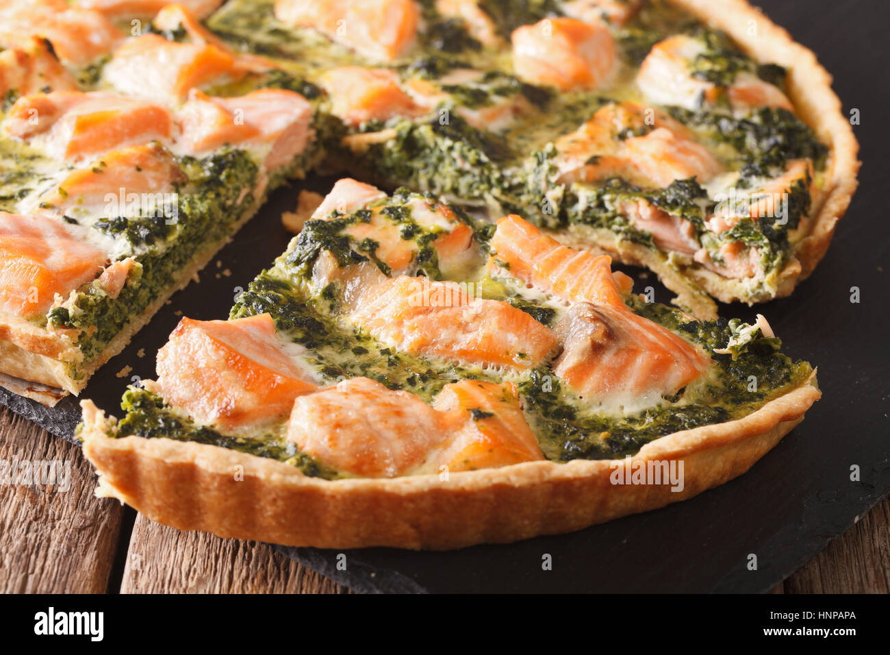 Herzhafte Speisen: in Scheiben geschnitten-Tarte mit Lachs, Spinat und Sahne close-up auf dem Tisch. horizontale Stockfoto