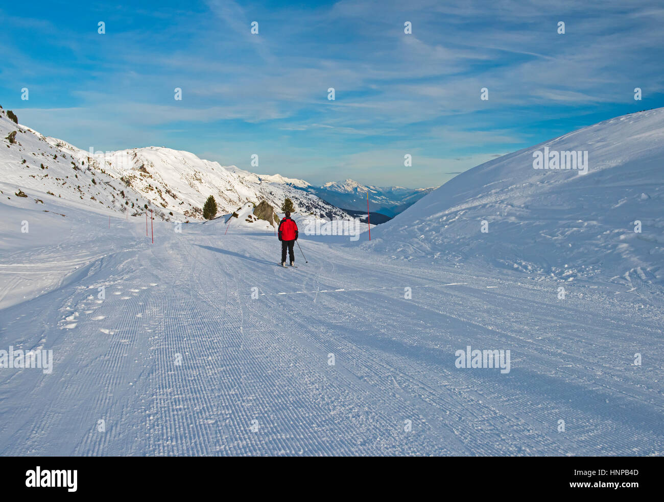 Skifahrer auf einer Skipiste Hang in alpine Wintersportort mit blauem Himmel Stockfoto