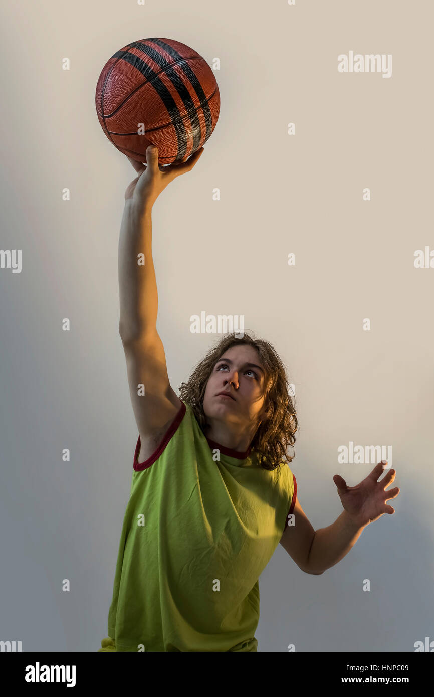 Junge mit langen blonden Haaren spielen Basketball in der markanten Lage mit ein grünes Trikot auf. Stockfoto