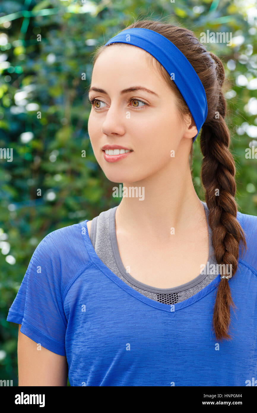Porträt von lächelnden sportliche Brünette Frau in blauen Sportbekleidung im Freien. Fit, sportlich und sportliche junge Frau. Schöne Mädchen in Sportkleidung. Frisur Stockfoto