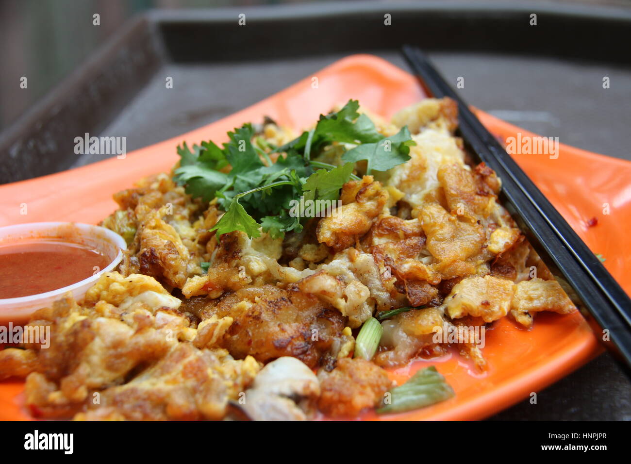 Auster Omelett oder Orh Luak. Beliebten Hawker / Nacht Markt Essen in Singapur. Garniert mit Koriander und mit Chili-Sauce serviert. Stockfoto