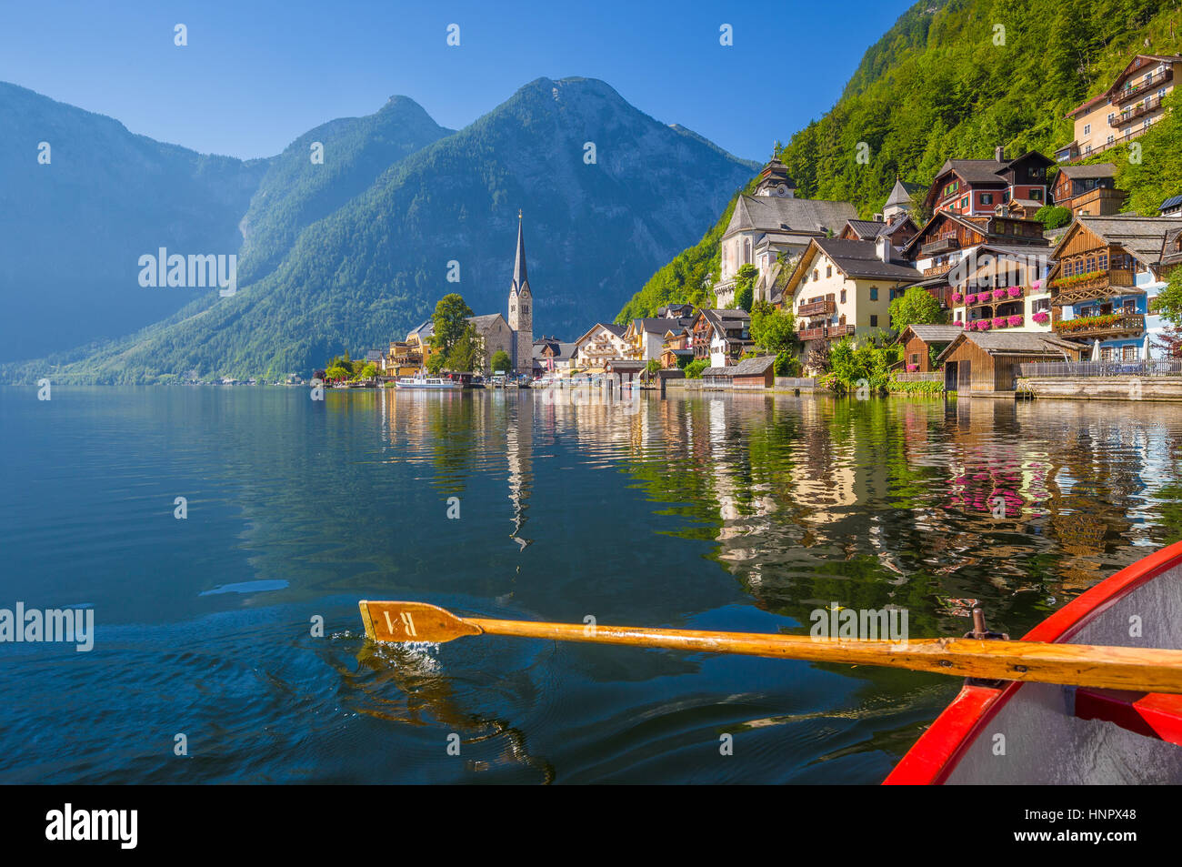 Malerische Postkartenblick auf berühmte Hallstätter See Dorf in den österreichischen Alpen mit traditionellen hölzernen Ruderboot im schönen Morgenlicht auf eine Sonne Stockfoto