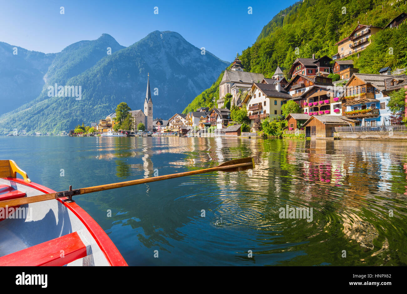 Malerische Postkartenblick auf berühmte Hallstätter See Stadt in den Alpen mit traditionellen hölzernen Ruderboot an einem schönen sonnigen Tag im Sommer, Österreich Stockfoto