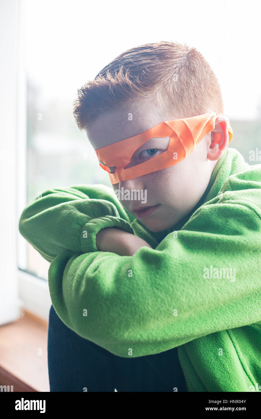 Ein 10 Jahre alter Junge gekleidet wie ein Superheld in einer orange-Maske. Stockfoto