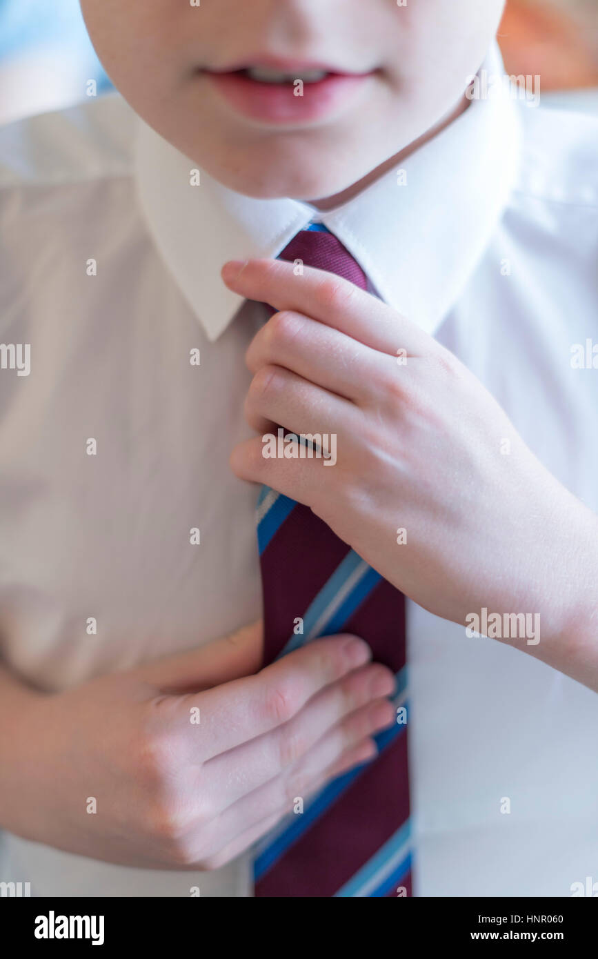 Ein Schuljunge seine Schule einheitliche Krawatte befestigen. Stockfoto