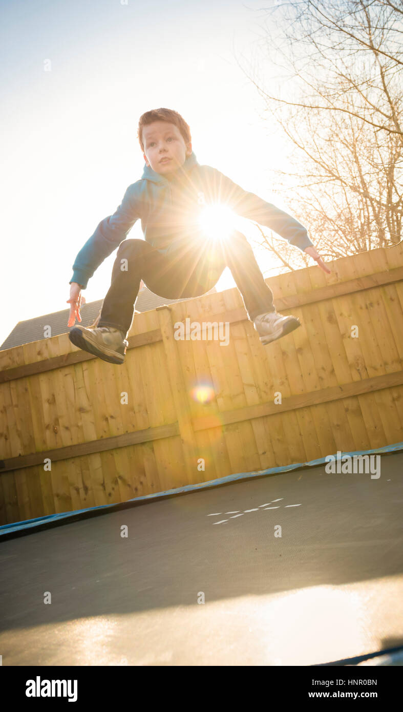 9-jähriger Junge springen auf einem Trampolin in seinem Garten. Stockfoto
