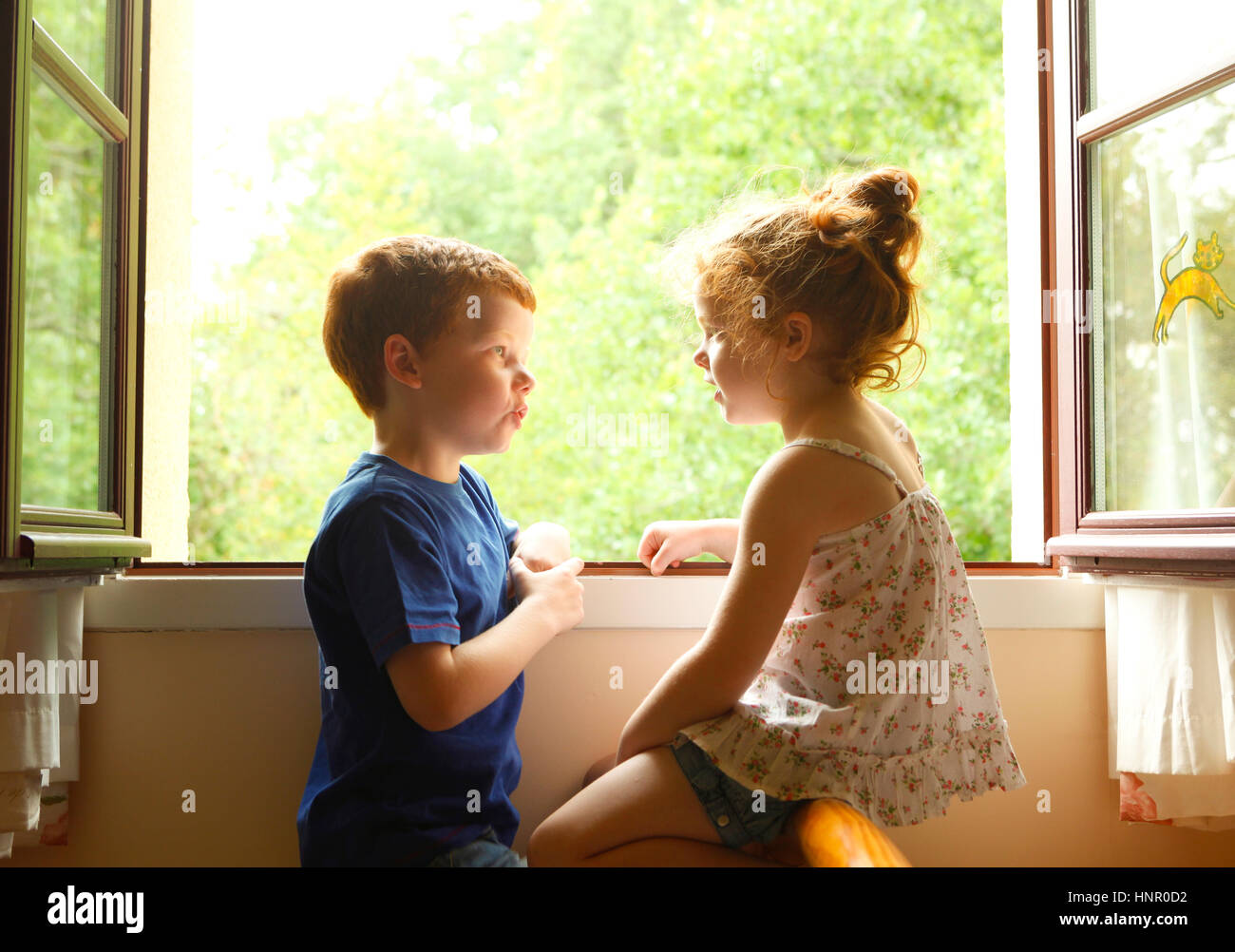 Bruder und Schwester miteinander zu reden, durch ein Fenster. Stockfoto