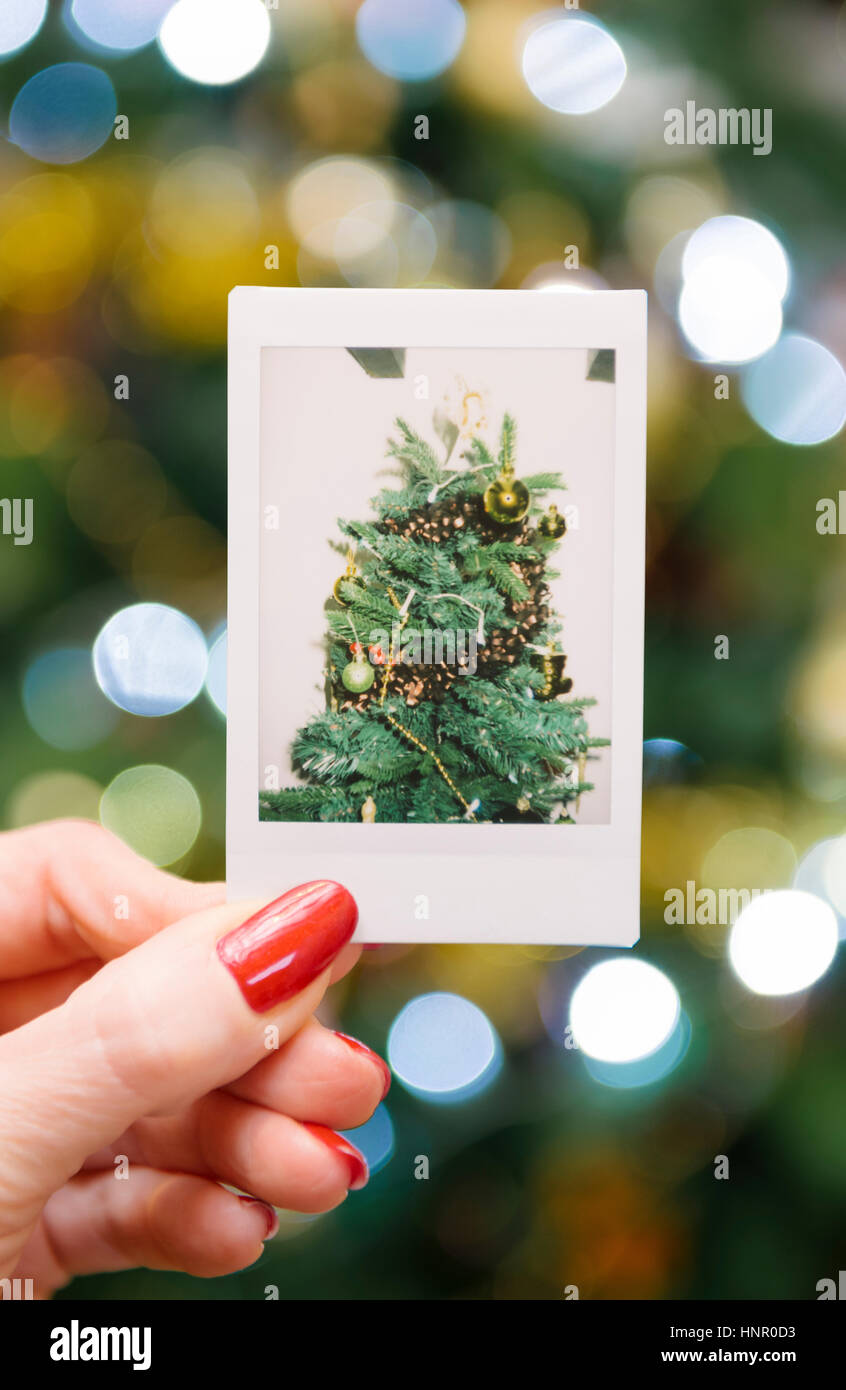 Frau mit einem sofortigen Druck eines Weihnachtsbaumes vor dem Baum Stockfoto