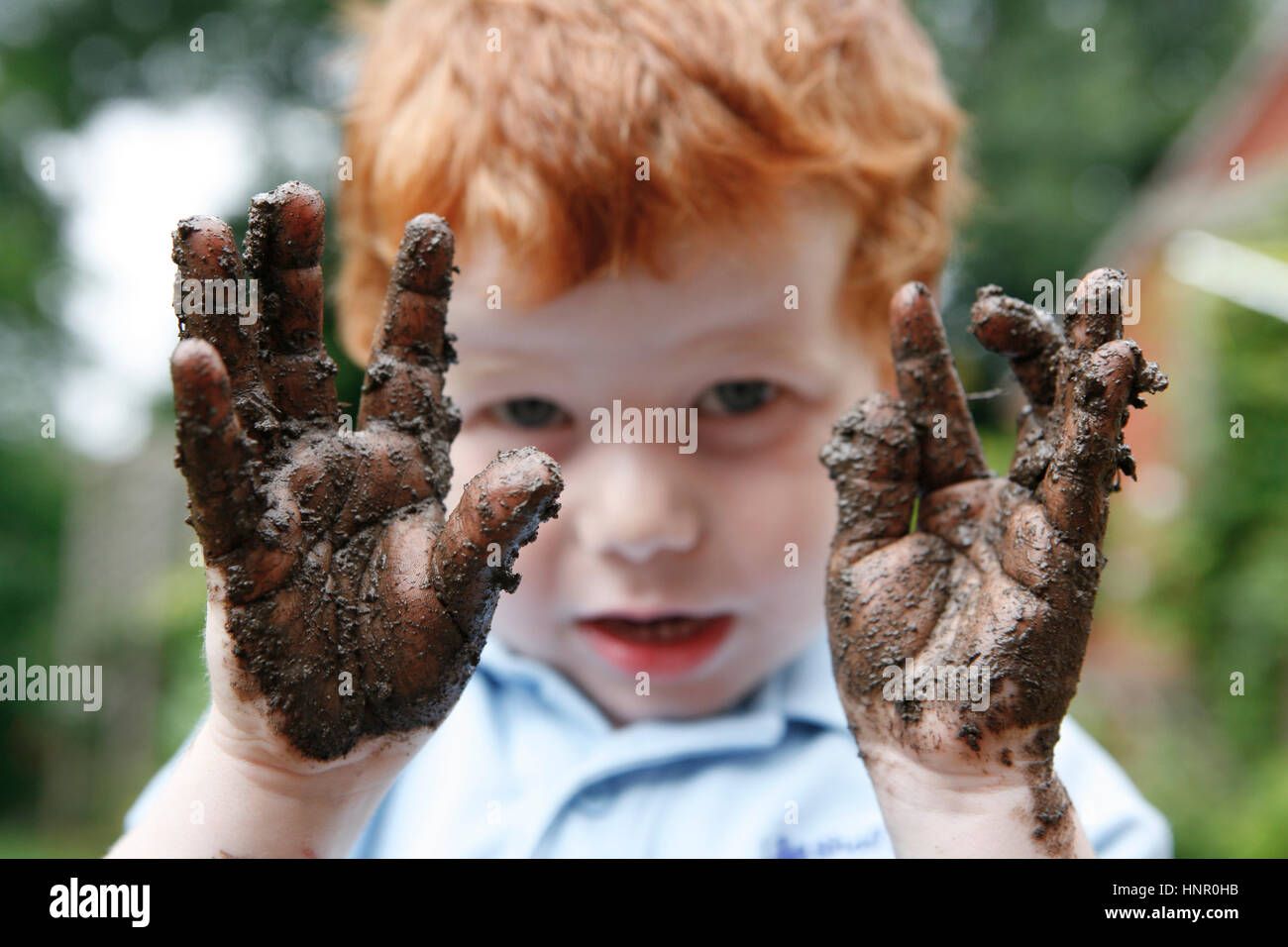 Ein Kind hält seinen schlammigen Hände Stockfoto