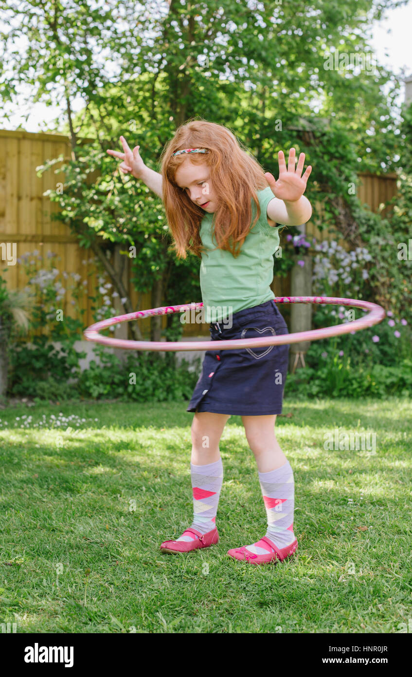 Kleine Mädchen spielen mit einem Hula-Hoop in ihrem Garten Stockfoto