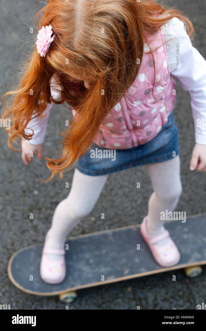 6 Jahre altes Mädchen mit roten Haaren auf dem skateboard Stockfoto