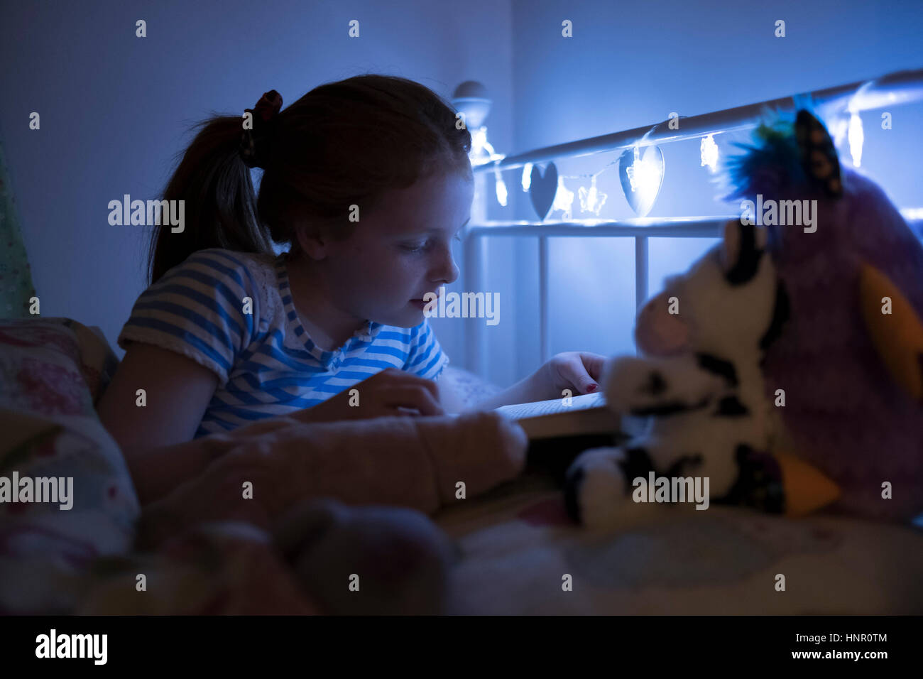Ein kleines Mädchen, ein Buch zu lesen, vor dem Schlafengehen. Stockfoto