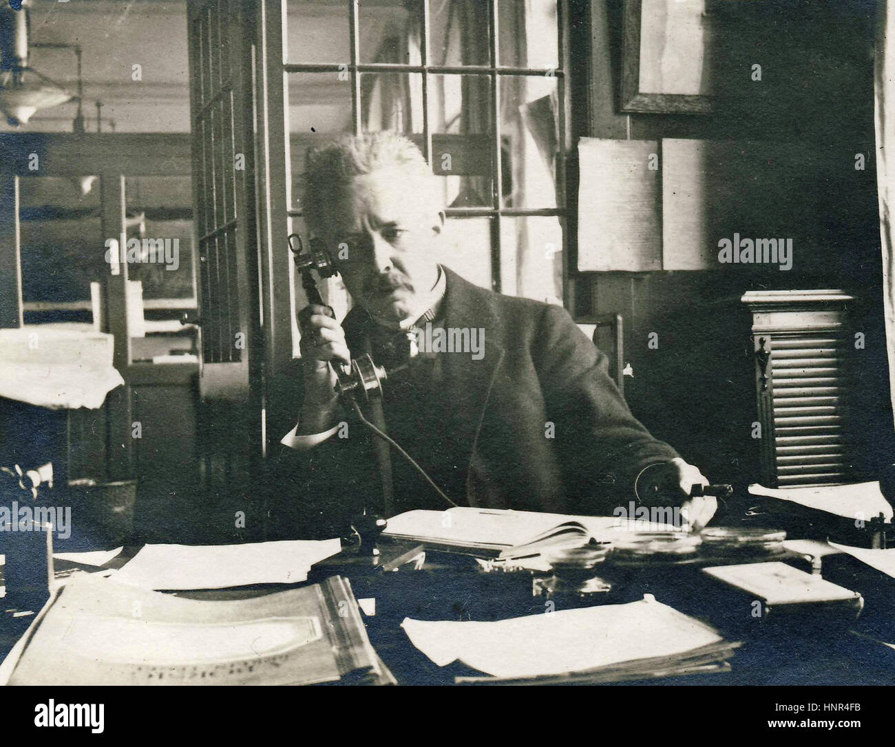 Archiv-Bild des Menschen sitzen am Schreibtisch mit frühen Telefon Stockfoto