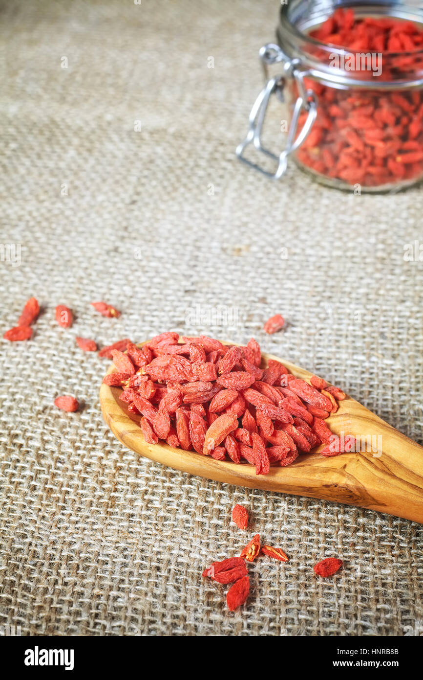 Getrocknete Gojibeeren auf einem Löffel aus Holz, Leinen Hintergrund, selektiven Fokus. Goji-Beeren sind eine ausgezeichnete Quelle von Antioxidantien. Stockfoto