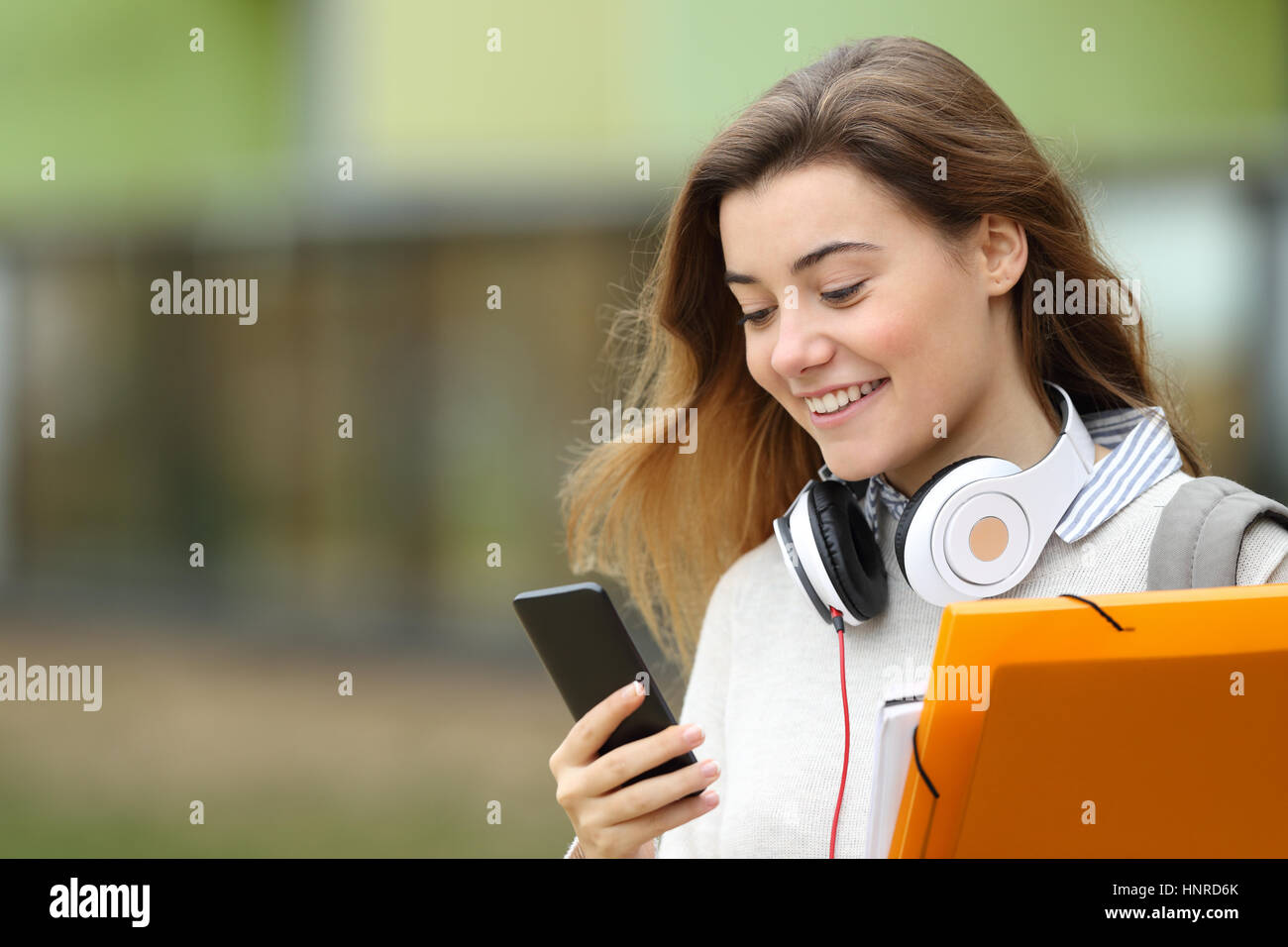Porträt eines lässig Studenten endet Klassen Wandern und SMS auf dem Handy mit der Universität Gebäude im Hintergrund Stockfoto