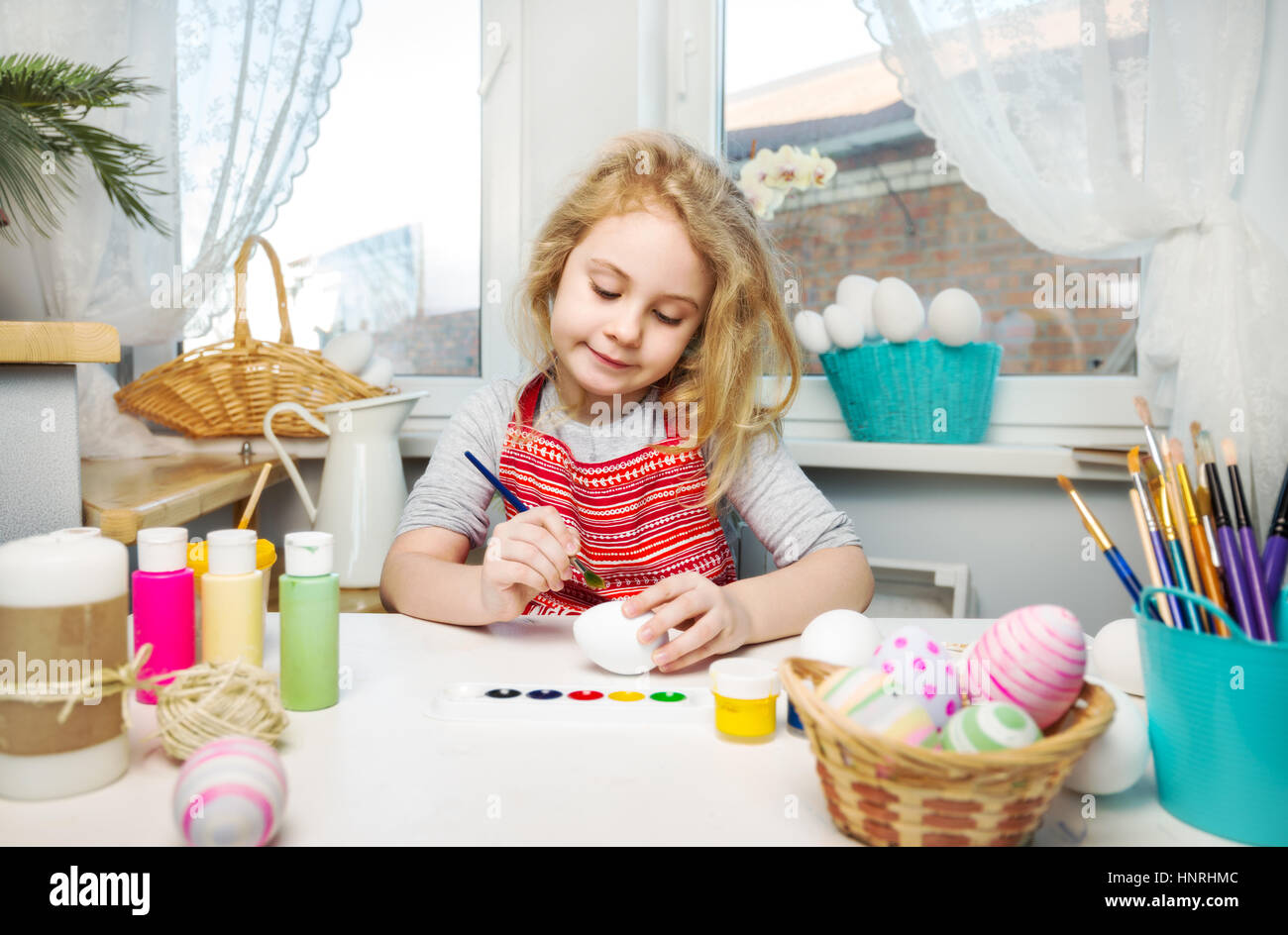 Kleine blonde Mädchen Färbung Eiern für Osterurlaub zu Hause Stockfoto