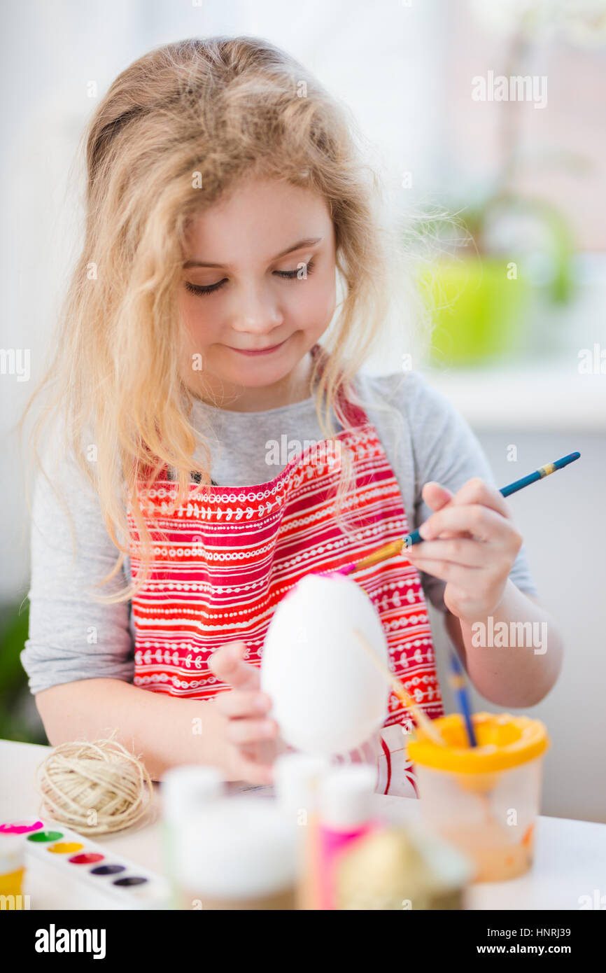 Kleine blonde Mädchen Färbung Eiern für Osterurlaub zu Hause Stockfoto
