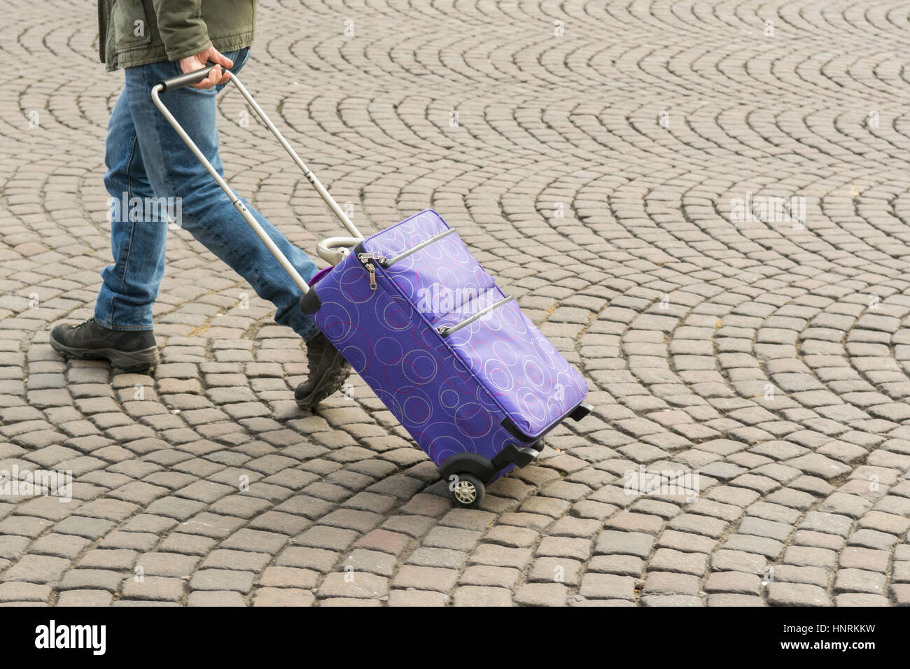 männliche Touristen ziehen Rädern Koffer über Kopfsteinpflaster Stockfoto