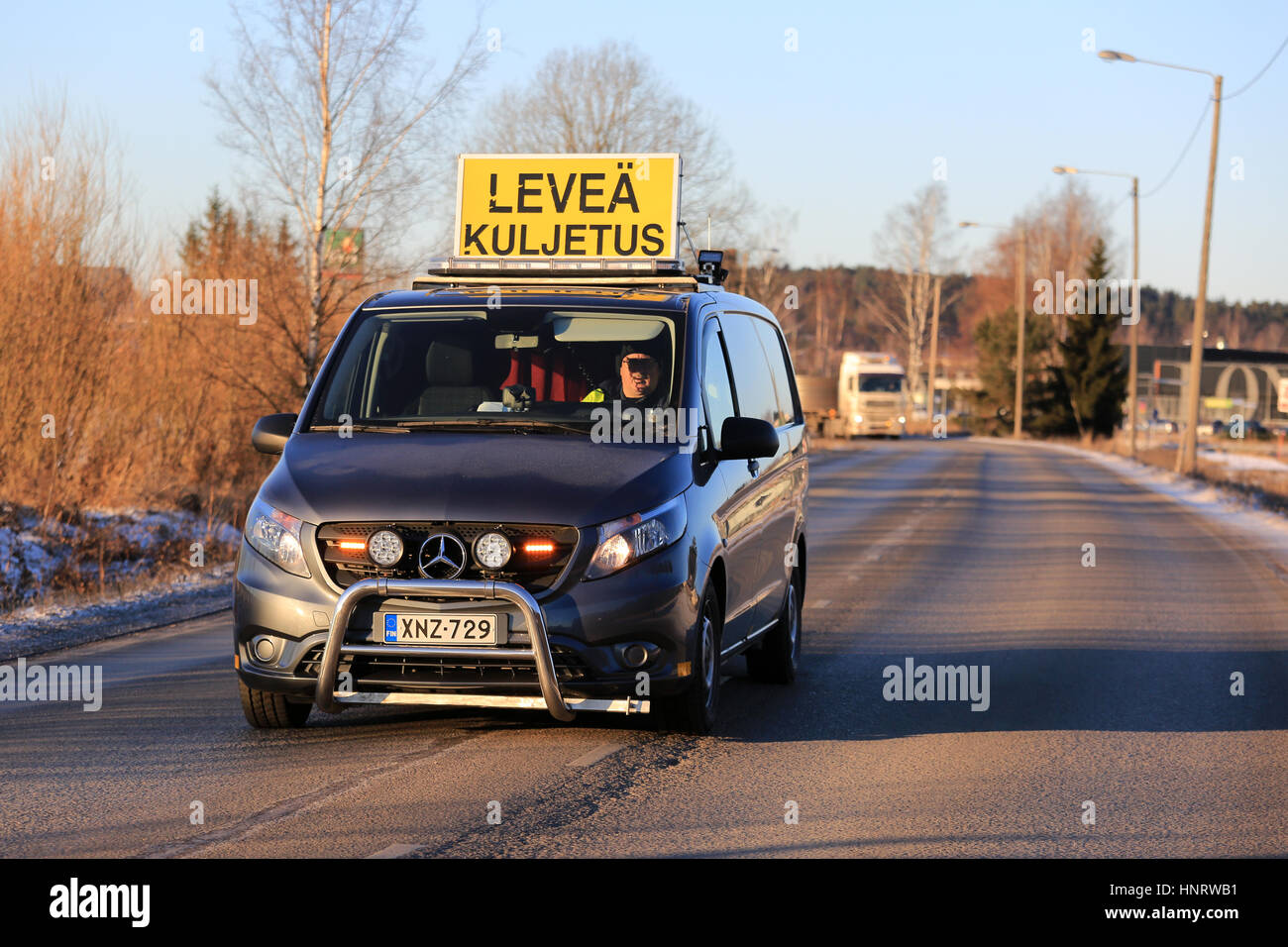 SALO, Finnland - 5. Januar 2017: Mercedes-Benz Sprinter van Begleitfahrzeug mit blinkenden Lichtern Laufwerke vor der Zugmaschine und Anhänger große Last Transport. Stockfoto