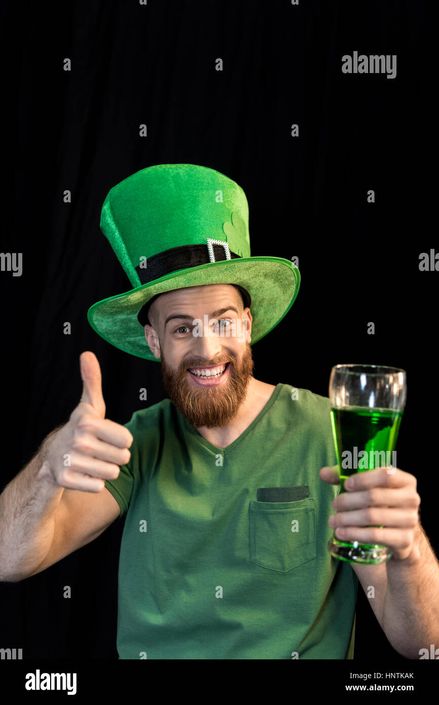 Mann hält Glas Bier am St. Patrick es Tag und Daumen auftauchend auf schwarz Stockfoto
