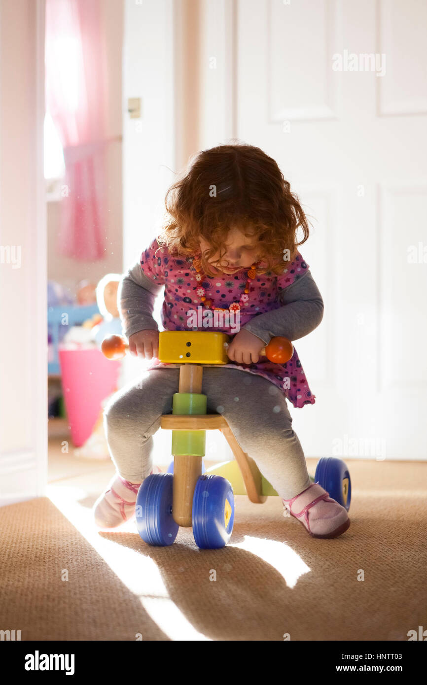 Ein zwei Jahre altes Mädchen spielen auf ein Trike in einem Haus Stockfoto