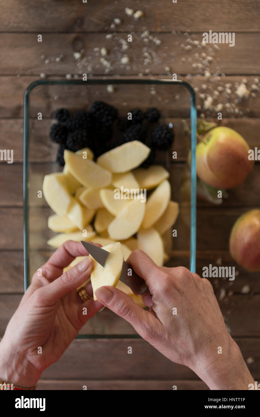 Eine Frau bereitet ein Fruchtpudding bröckeln. Schneiden Äpfel. Stockfoto