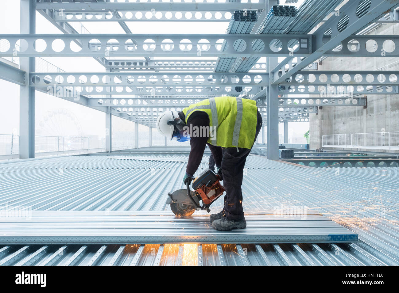 Workman schneiden Stahl Bodenbelag auf einer Baustelle in Schutzkleidung Stockfoto