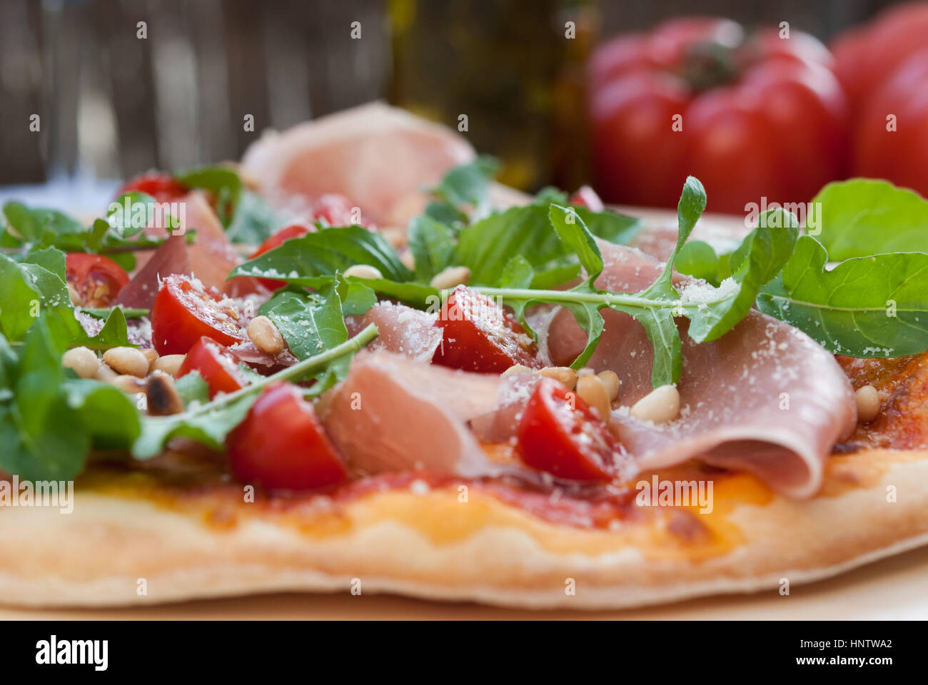Pizza Prosciutto - Rucola auf einem Holzbrett closeup serviert. Stockfoto