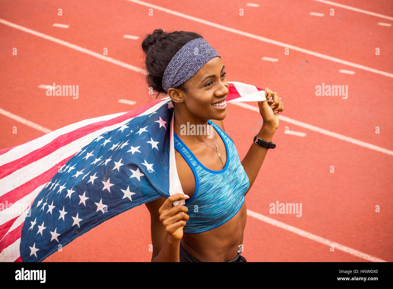 Lächelnd schwarzer Athlet Holding amerikanische Flagge auf dem richtigen Weg Stockfoto