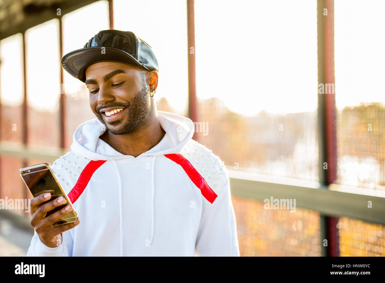 Lächelnde schwarzer Mann SMS auf Handy Stockfoto