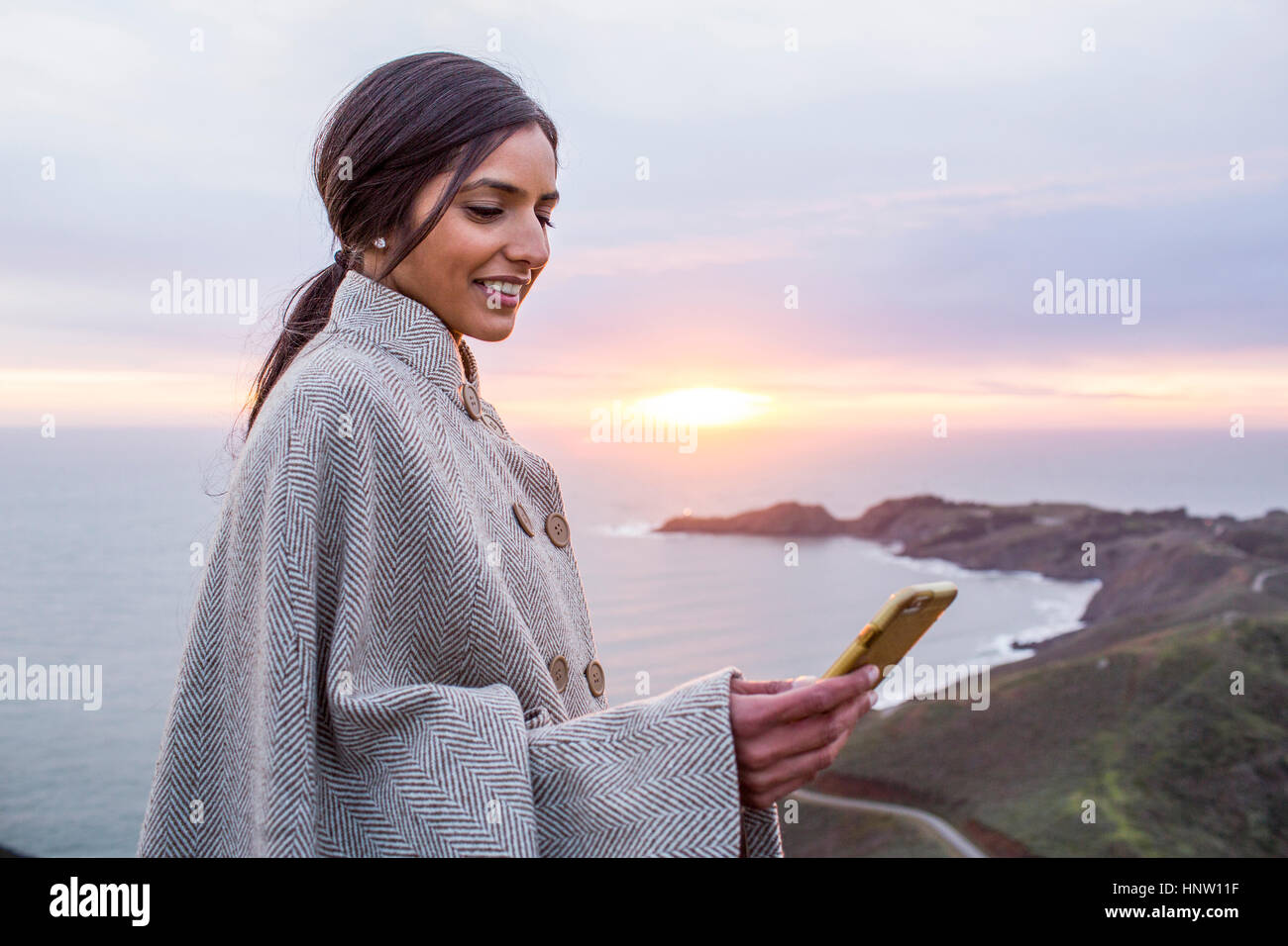 Lächelnden Inderin SMS auf Handy in Küstennähe Stockfoto