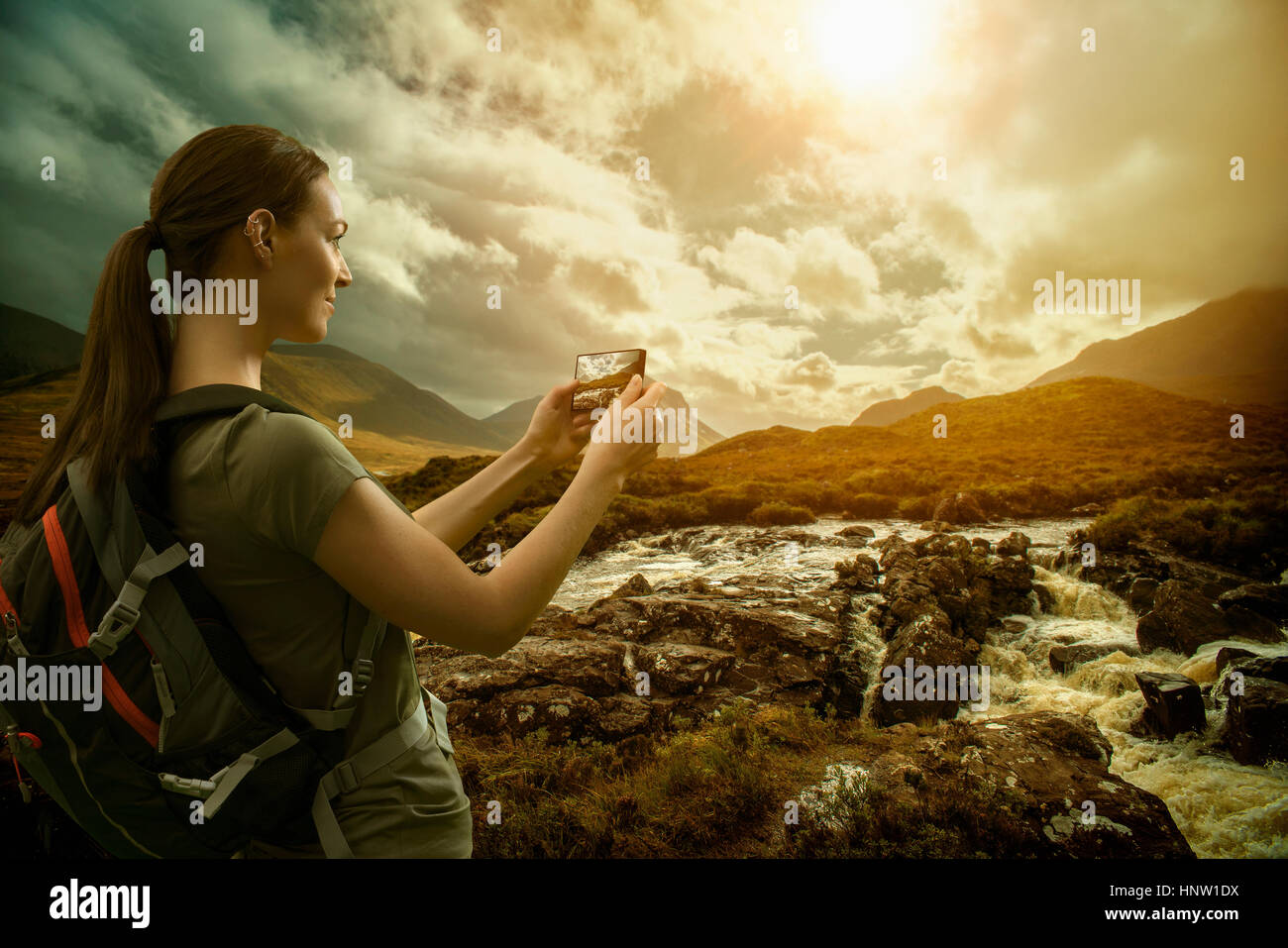 Kaukasische Frau fotografieren Gebirgsfluss mit Handy Stockfoto
