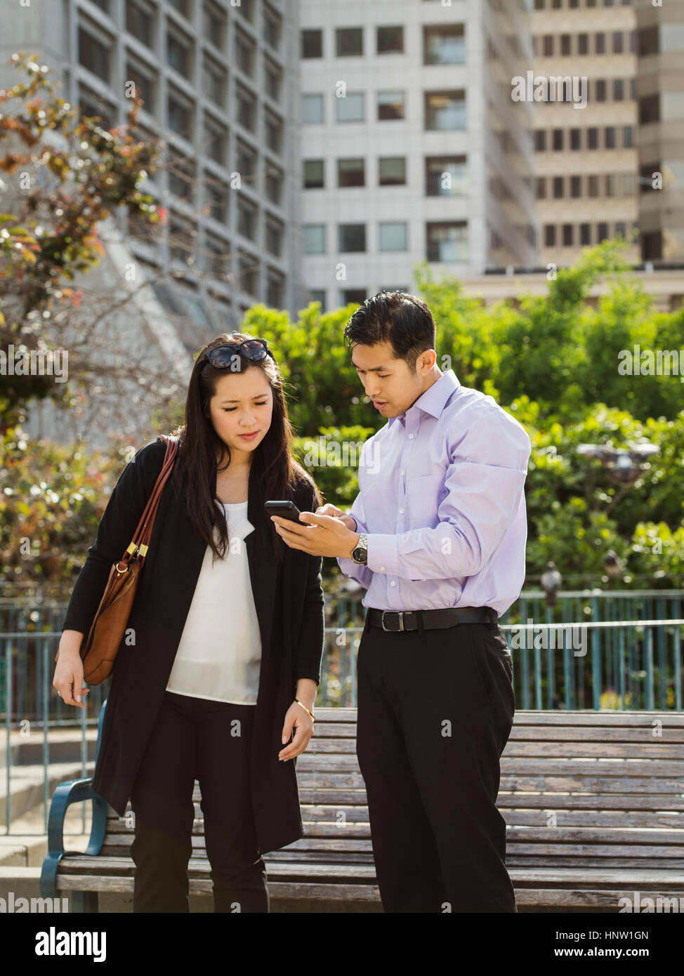 Chinesische Geschäft Leute SMS auf Handy in der Nähe von City Bank Stockfoto