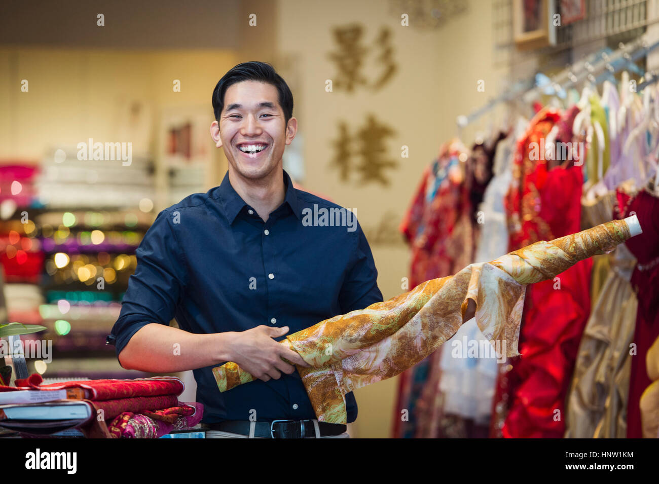 Lächelnde chinesische Mann posiert mit Stoff im store Stockfoto