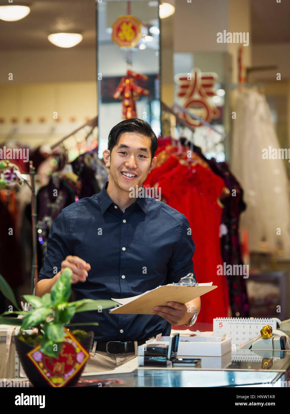 Lächelnde chinesische Mann schreiben in Zwischenablage im store Stockfoto