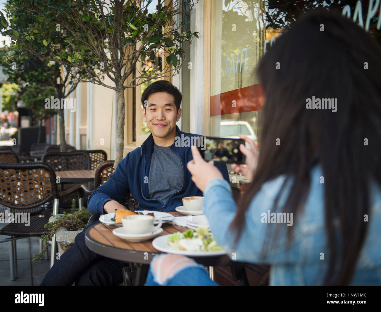 Chinesische Frau Mann in Straßencafé mit Handy fotografiert Stockfoto